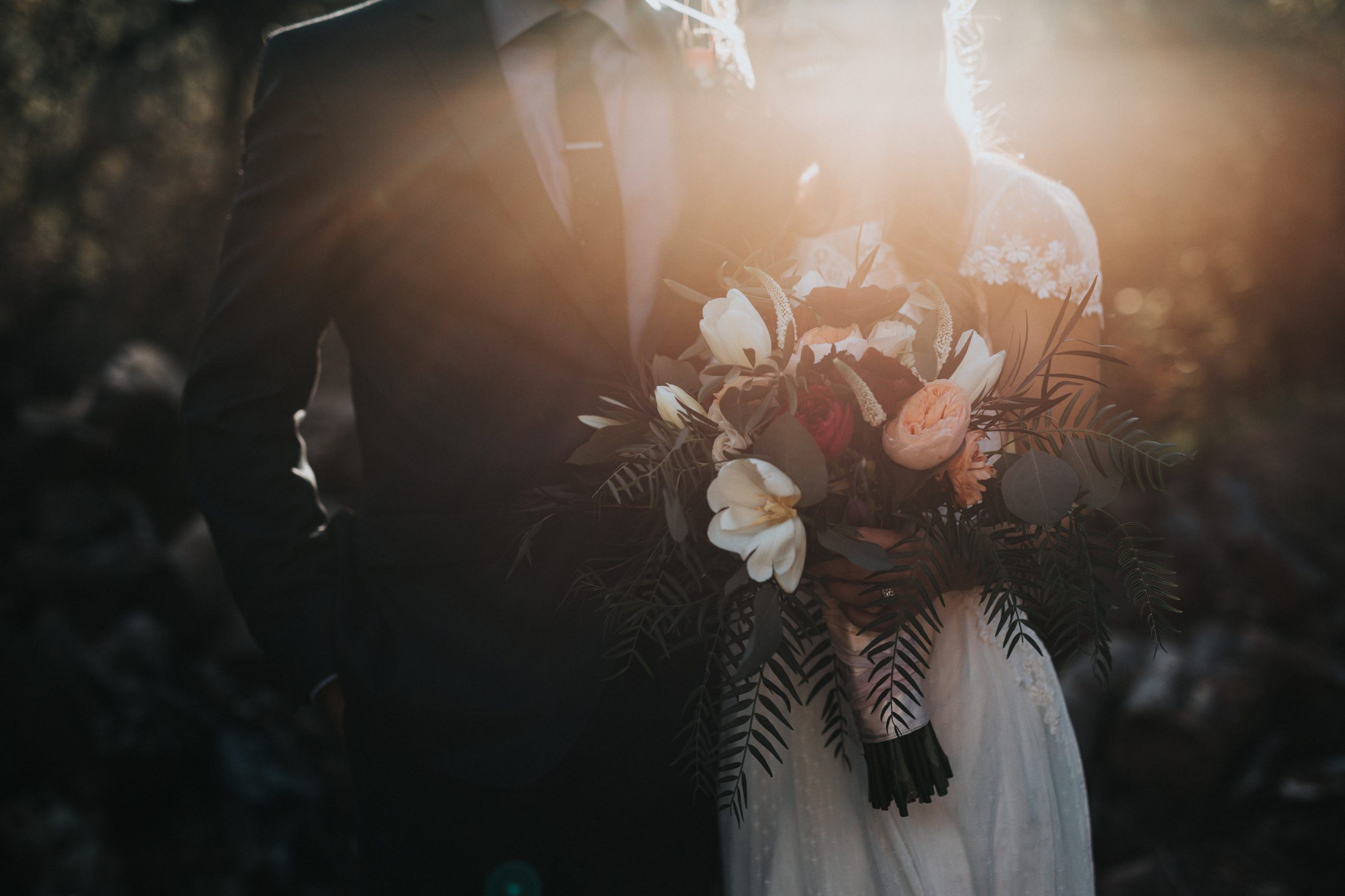 Married couple posing together with the sun setting in the background.