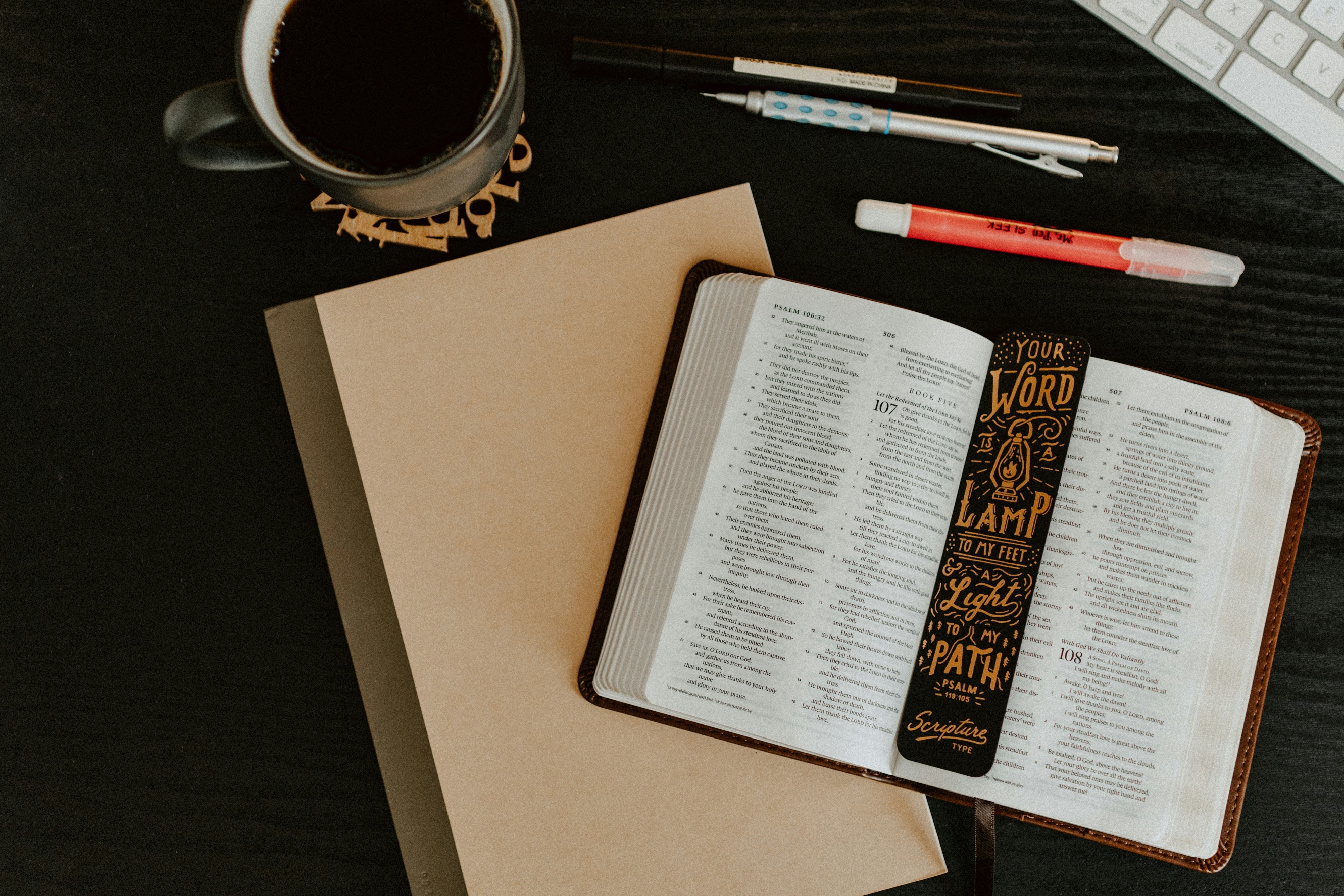 Open bible with highlighters, notebook, and a journal for note taking.