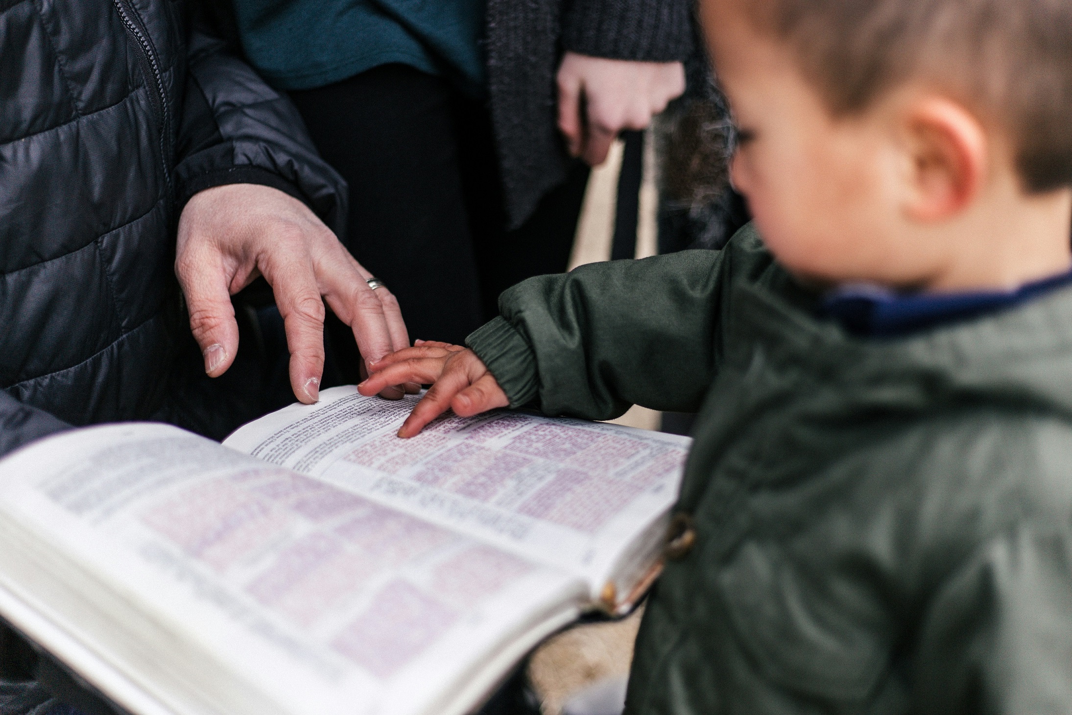 A man reading the Bible to a little boy.