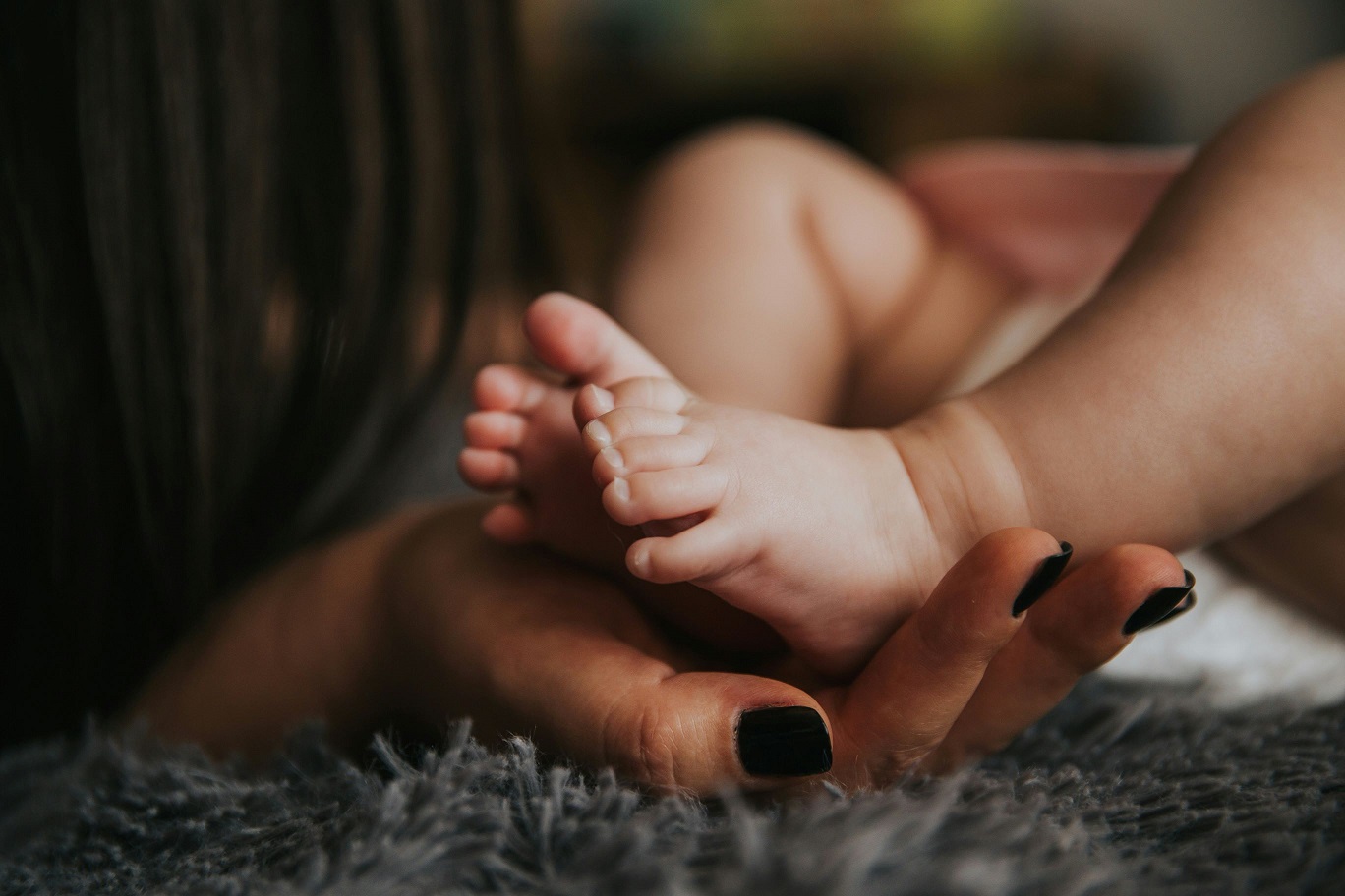 A mother holding the feet of her newborn baby.